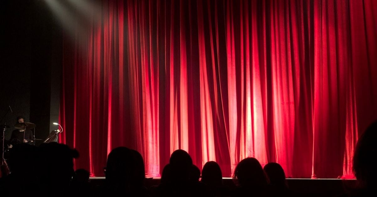 Red theatre curtain with silhouettes of viewers heads below